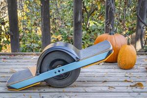 one-wheeled electric skateboard on a wooden backyard deck with pumpkins photo