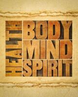 health, body, mind and spirit word abstract - a collage of text in vintage wood letterpress printing blocks on art paper, wellbeing and personal development concept photo
