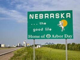 Nebraska, the good life, home of Arbor Day - roadside welcome sign at state border with Colorado, summer scenery with a rural town in background photo