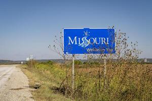 Misuri da la bienvenida usted - un borde del camino firmar a un estado frontera con Nebraska, otoño paisaje con seco girasoles foto