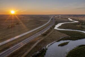 sunrise over a river meandering through Nebraska Sandhills, highway and railroad - aerial view of Middle Loup River near Halsey photo