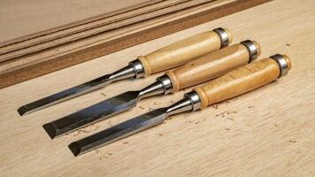 set of wood chisels against okoume plywood - woodworking concept photo