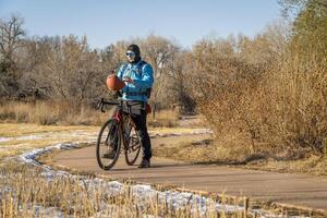 mayor masculino ciclista con un turismo grava bicicleta en un andar en bicicleta sendero en fuerte collins, Colorado en frío otoño clima con algunos nieve foto