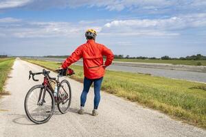 atlético hombre es montando un grava turismo bicicleta - andar en bicicleta en un dique sendero a lo largo cadena de rocas canal cerca granito ciudad en Illinois foto