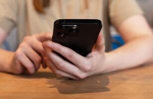 Berlin Germany January 21 2024 Hands at wood table, using smartphone, mobile phone, iphone closeup photo