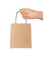 Hand holding, giving, presenting small gift bag, kraft package isolated on white photo