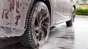 Part of car during washing with shampoo, water and foam dripping from the car. High quality 4k footage video