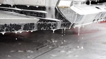 Part of car during washing with shampoo, water and foam dripping from the car. High quality 4k footage video