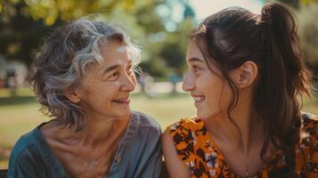 Old mother with young woman sitting on a bench and smiling at each other photo