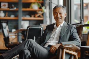 Mature Asian smart businessman sitting in modern office. Business people concept photo