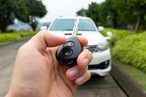 Car key in hand with car on the background. Car stuff concept. After some edits. photo