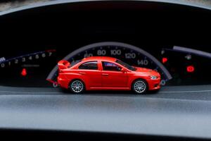 Red toy car inside a real car with speedometer background. After some edits. photo