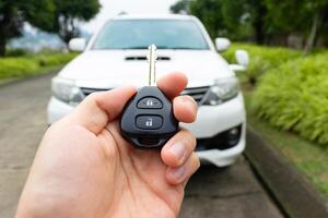 Car key in hand with car on the background. Car stuff concept. After some edits. photo