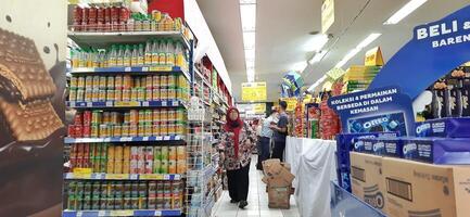 cliente elegir varios comestibles productos en tienda de comestibles almacenar. supermercado concepto. bekasi, Oeste Java, Indonesia - marzo 8 2024 foto