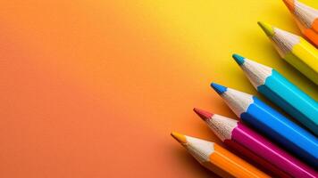 Colorful pencils on orange background. Back to school concept. photo