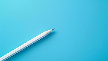 White pencil isolated on blue background with copy space for your text. photo