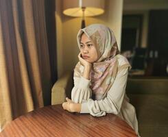 Asian Muslim woman wearing hijab having bad mood, upset tired bored expression, with blur background photo