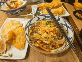 Traditional Japanese noodle soup Niku Udon with beef sukiyaki, tempura, and sliced spring onion and chili photo