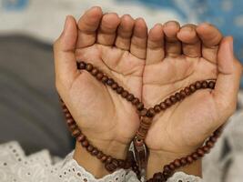 A young Asian Muslim woman holds prayer beads and prays during the fasting month of Ramadan photo