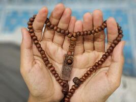 A young Asian Muslim woman holds prayer beads and prays during the fasting month of Ramadan photo