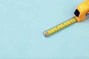 The yellow measuring tape for the mason is placed on a blue background. Soft focus. photo