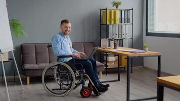 désactivée la personne pigiste est travail avec portable dactylographie séance dans fauteuil roulant à bureau. loin travail et invalidité concept video