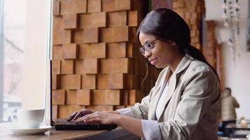 giovane arabo donna utilizzando il computer portatile computer nel bar. femmina professionale Lavorando con taccuino video