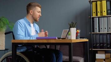 Cheerful disabled person talking on chat while sitting at office in a wheelchair video