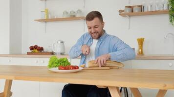 Cheerful disabled person in a wheelchair cuts bread in the kitchen video