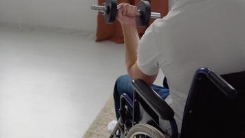 Disabled athlete in wheelchair performs exercises with dumbbells, home training and physical activity video