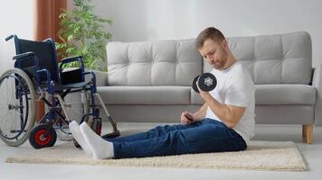 Disabled athlete performs exercises with dumbbells on wheelchair background. Home training and physical activity video