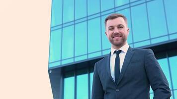 Portrait of a confident man in a business suit in front of a modern office building. Cityscape background video