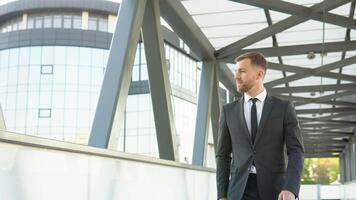 Confident attractive businessman goes outside near a large office building and looks around video