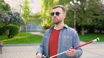 Blind man setting up walking cane in park. Independence concept video