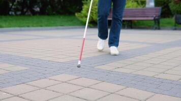 Blind man walking with a cane at the park. Male person wearing glasses and casual clothes. Independence concept video