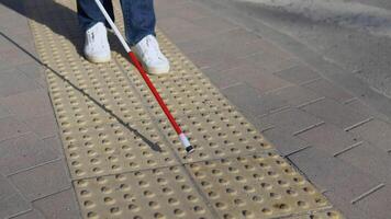 ben av blind person sökande särskild taktil plattor använder sig av sockerrör. blind man gående med en sockerrör i de gata video