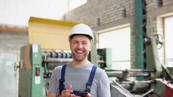 A cheerful professional worker sings and dances in an industrial workshop video