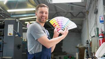 Porträt von ein Ingenieur auf ein Drucken Fabrik mit Farbe Palette. Konzept von Farbe Verwaltung im das drucken Produktion Verfahren. Katalog Proben zum Drucken Proofing video