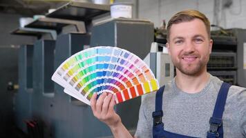 Porträt von ein Ingenieur auf ein Drucken Fabrik mit Farbe Palette. Konzept von Farbe Verwaltung im das drucken Produktion Verfahren. Katalog Proben zum Drucken Proofing video