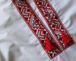 Closeup photo of fragment of Ukrainian traditional vyshyvanka shirt embroidered with red and black threads