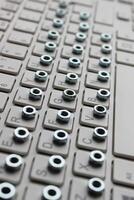Vertical Stock Photo Of Small Hex Nuts Laid Out In Order On A Keyboard