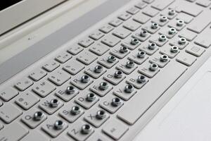 Shiny nuts stacked on white laptop keys angle view stock photo