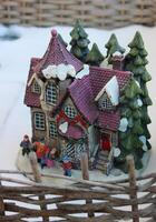 Toy winter yard fenced wattle hedge with a house and family figurines on the porch photo