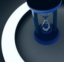 Top View Of Blue Sand Flows Down In A Blue Sandglass In Circle Of Light photo