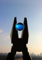 A blue crystal ball held in pliers as a symbol of an environmental conservation photo