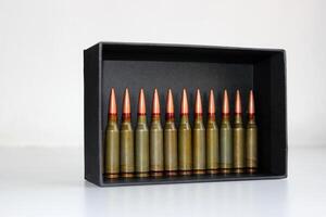 A row of live ammunition stands in a black case on a white background photo