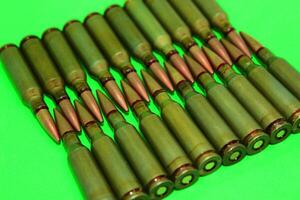 Even rows of live ammunition lined with bullets to bullets on a green surface photo