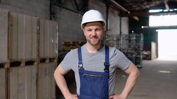 Portrait of a frontline essential worker in a warehouse. In the background big warehouse video