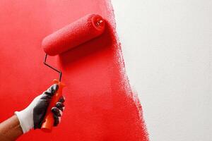 Roller Brush Painting, Worker painting on surface wall Painting apartment, renovating with red color paint. Leave empty copy space white to write descriptive text beside. photo