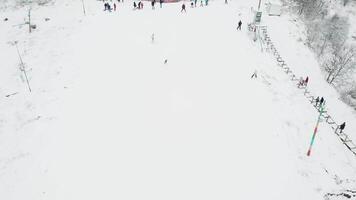 People skiing on a slope at ski resort. Aerial video